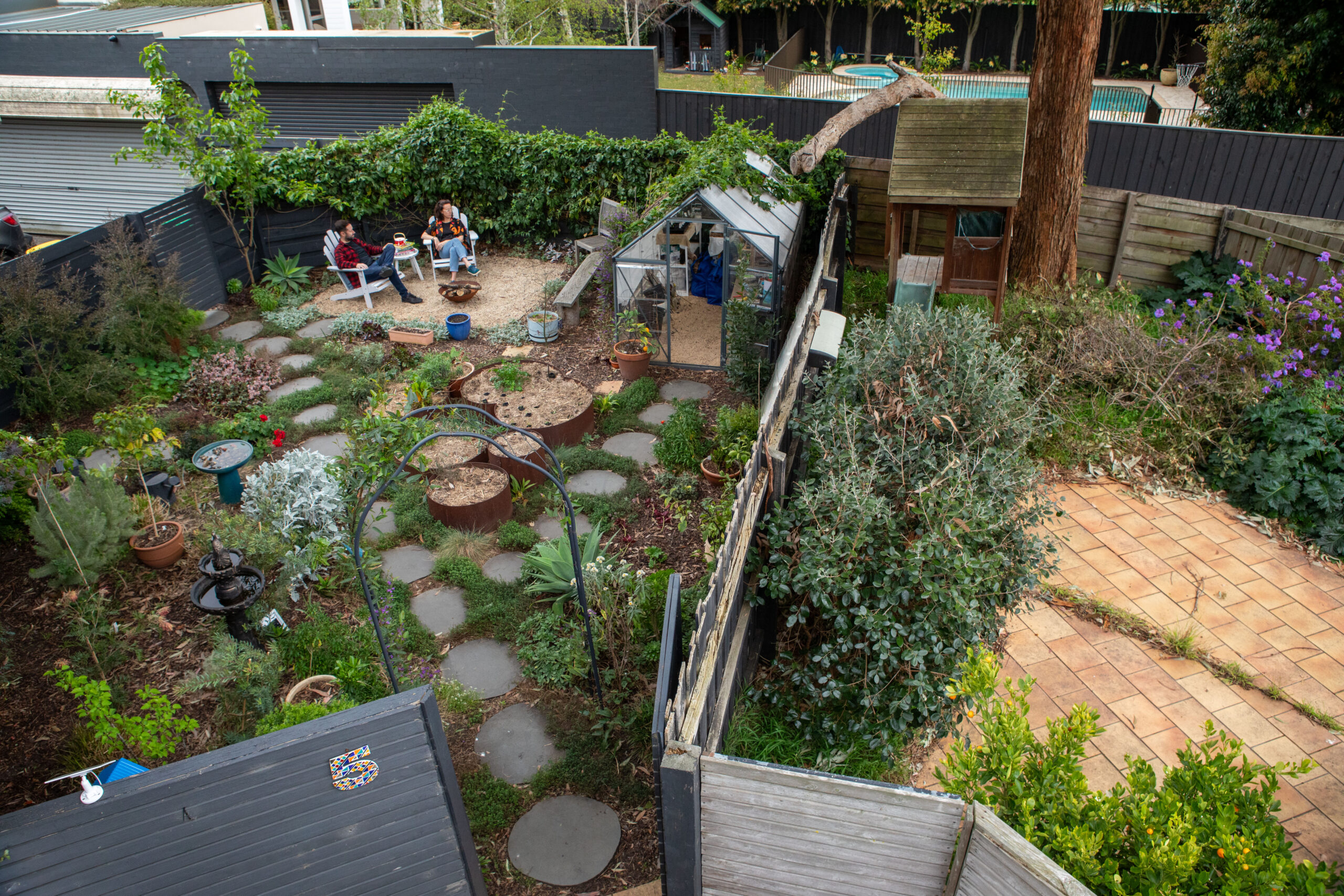 An aerial image of two courtyard gardens; one has been covered with planters and herbs while the other is plain and paved.